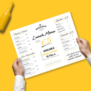 Two hands holding a lunch menu with price lists on with a yellow background.